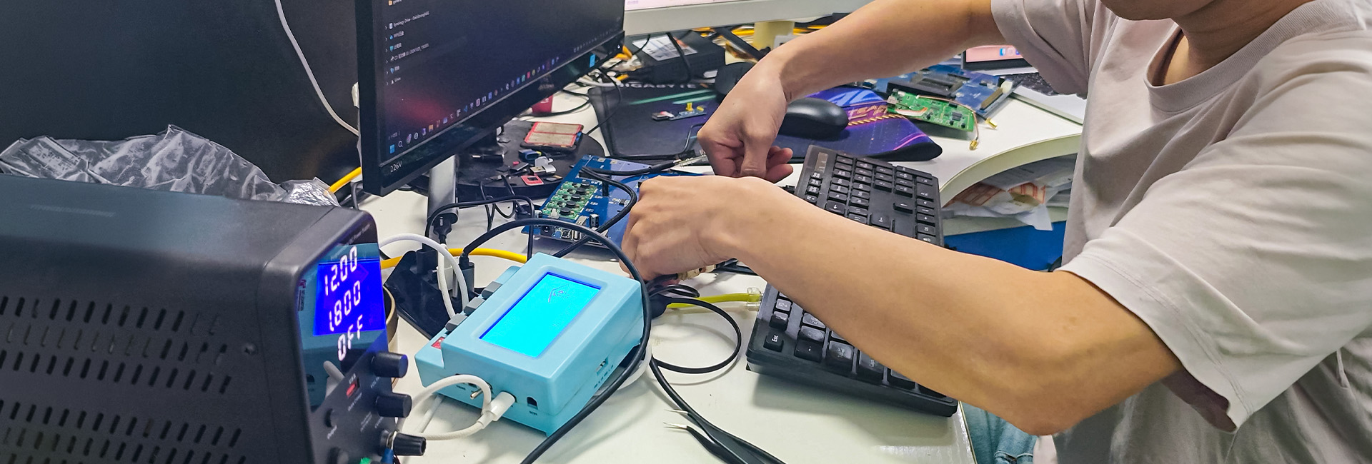 Engineer connecting wires to a testing instrument at a workbench in GMIC's Shenzhen engineering office