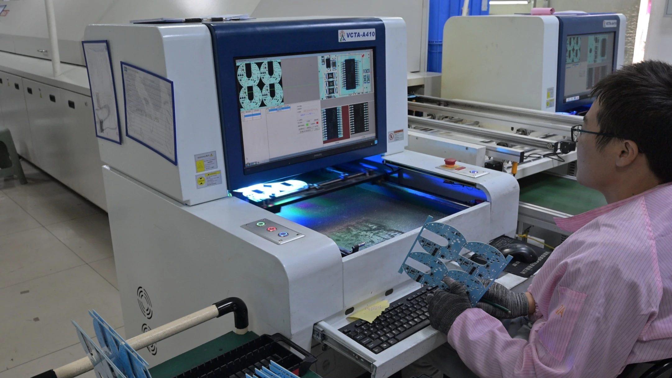 Operator running an automated optical inspection machine on assembled boards